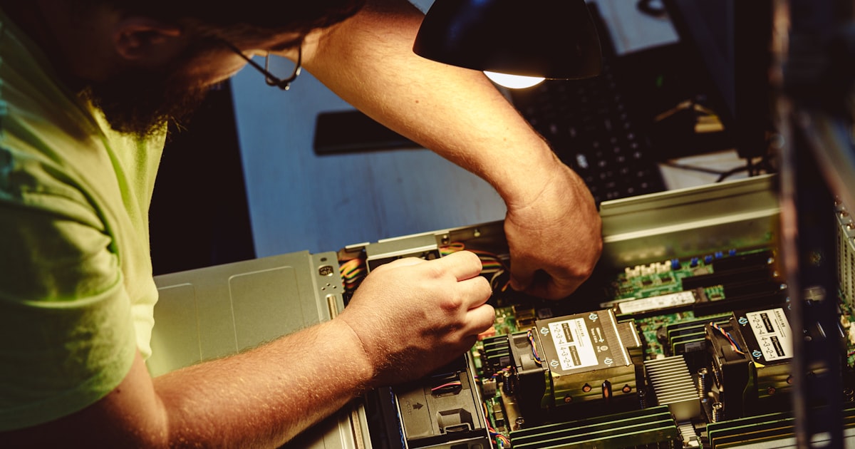 Engineer repairing a server under a lamp